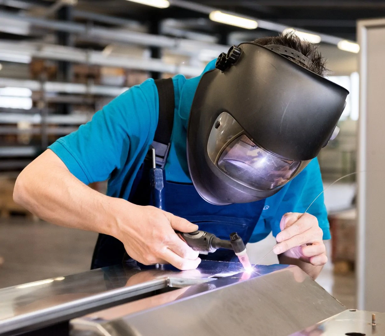 Pracownik wykonujący spawanie laserowe elementów metalowych w zakładzie produkcyjnym Pracownik wykonujący spawanie laserowe elementów metalowych w zakładzie produkcyjnym